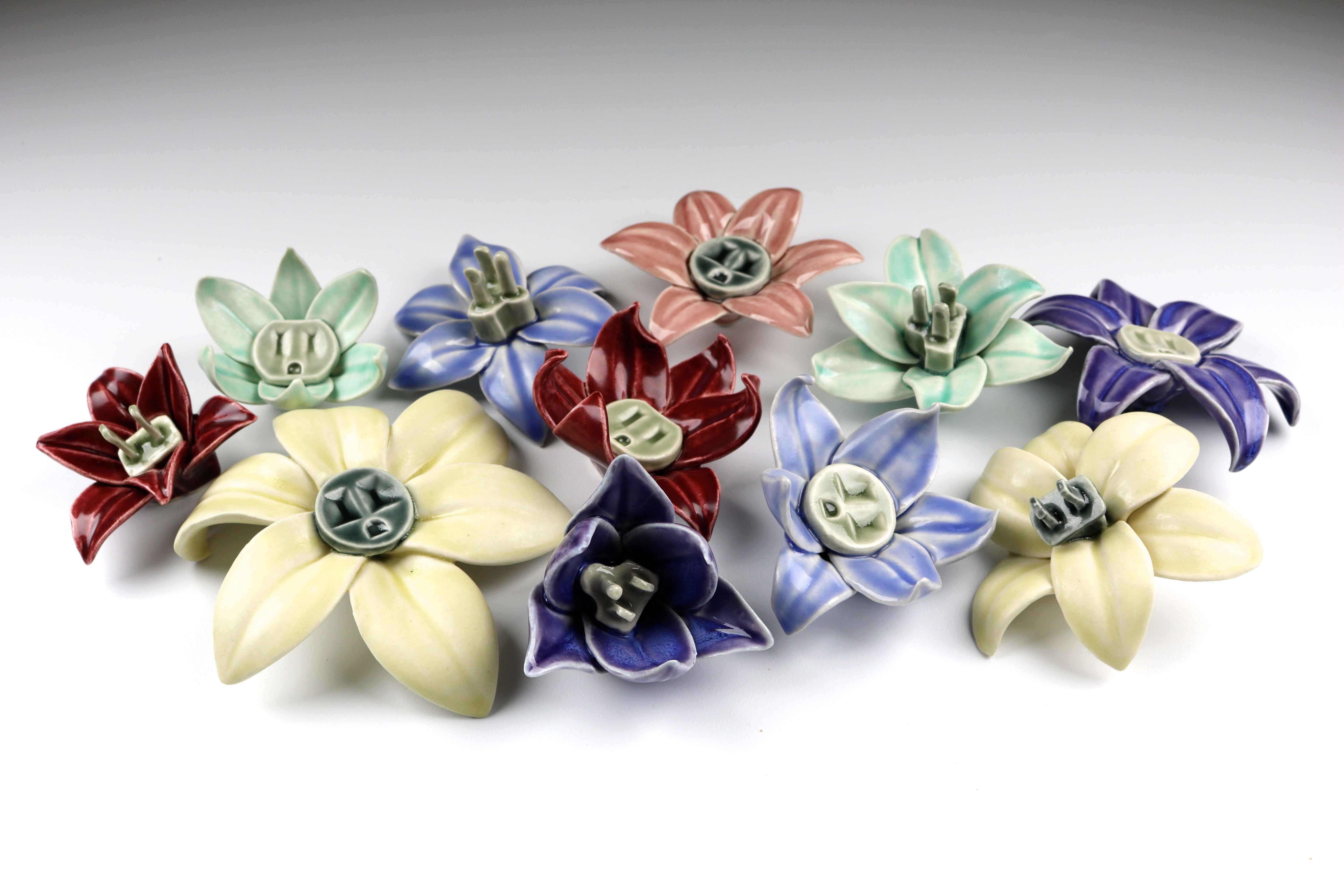 Flower Power by Julie K. Anderson (2017) multi-part porcelain sculpture, hand-built and press-molded with Cone 6 oxidation glazes; approx. 3x3x1.5 in. ea.  