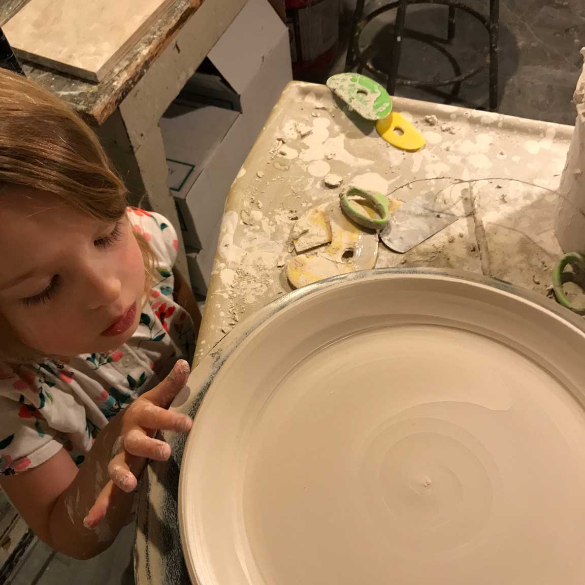 Kate Fisher's daughter inspects a freshly-thrown plate (by Kate).