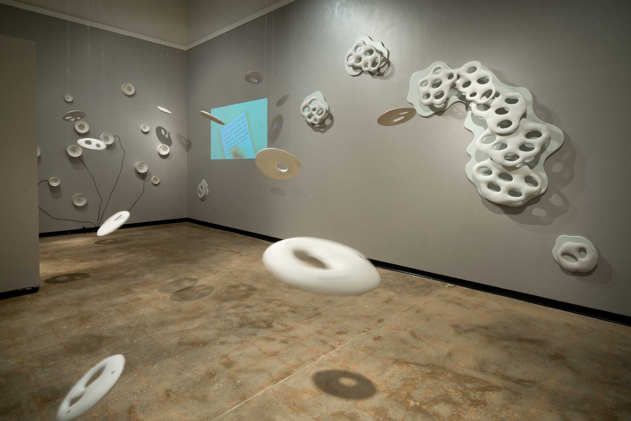 Nicole Gugliotti. Awe/Agency, 2014. Porcelain, Stoneware, wood, paint, video projection, audio, monofilament. Full installation, 10 x 25 x 14 ft. Photo by Allen Cheuvront.