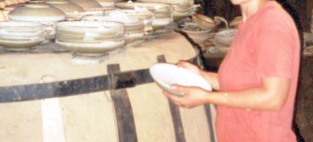 Alina Iorga, 1997, in her kiln building; pots are drying on top of the kiln.