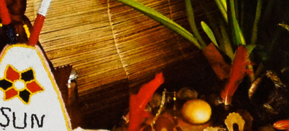 Osun pot offering arrangement, Yoruba/Lucumi deity of fresh water, 2013. Lidded pot 12 in, glazed earthenware, fruit, vegetables, drink, beadwork, statuary, floral arrangement, red parrot feathers. Photograph by Awo Fáladé Òsúntólá.