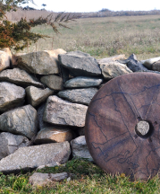 Ashwini Bhat’s Millstone I, 2015, in front of the stonewall rebuilt by Dr. Robert French by the Slocum river, Westport, Massachusetts. Stoneware, 26 in. diameter. Photo by author.