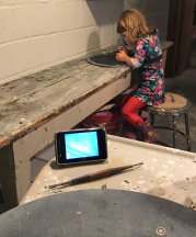 While she works in the studio, Kate monitors one kid in the studio, and the other through a digital device.