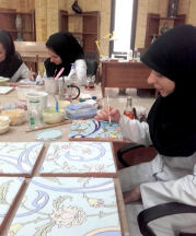 The Iran Cultural Heritage Handcraft and Tourism Organization operates a handicraft institute in Tehran to train and provide opportunities for work in heritage skills, such as a seven-color cuerda seca tile process on which these women are working.