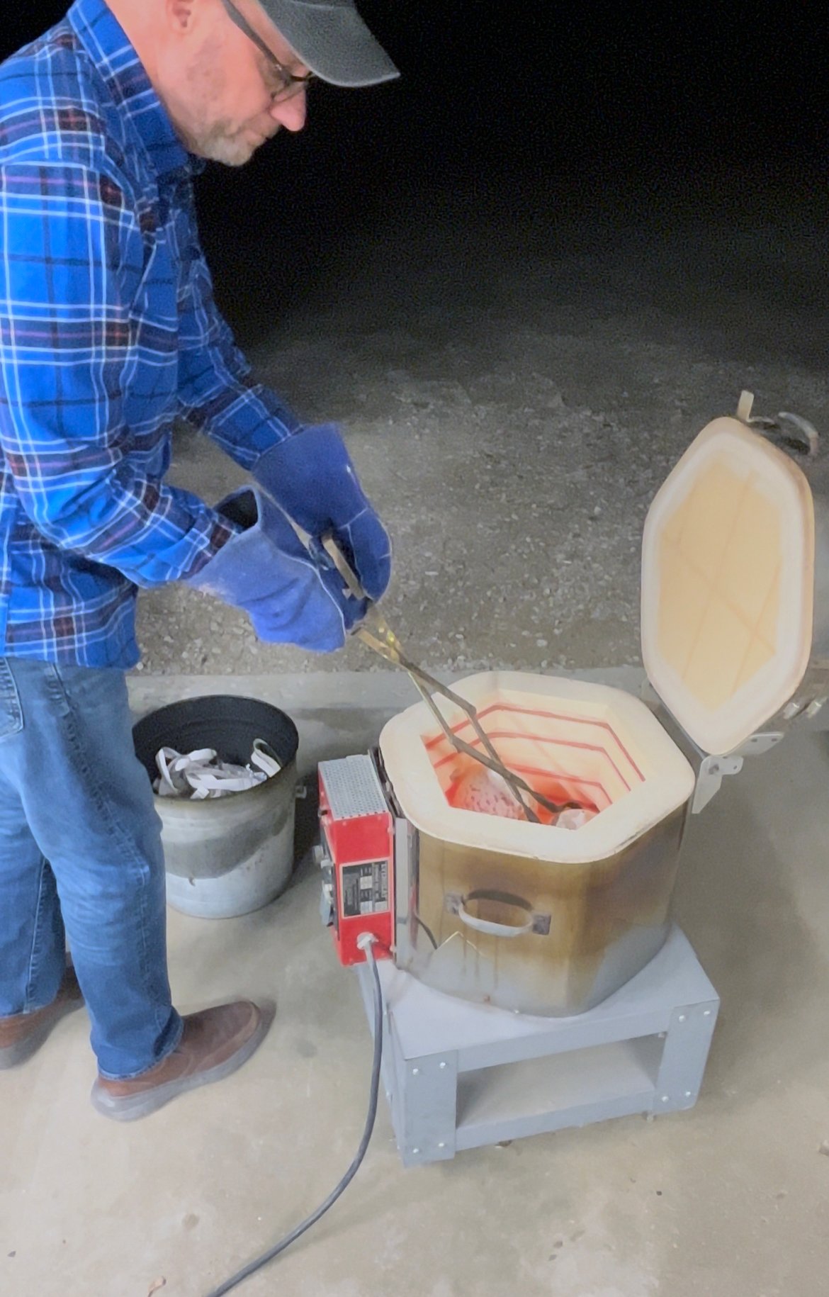 Artist Frank James Fisher pulling raku fired ceramic bottles from his electric kiln.