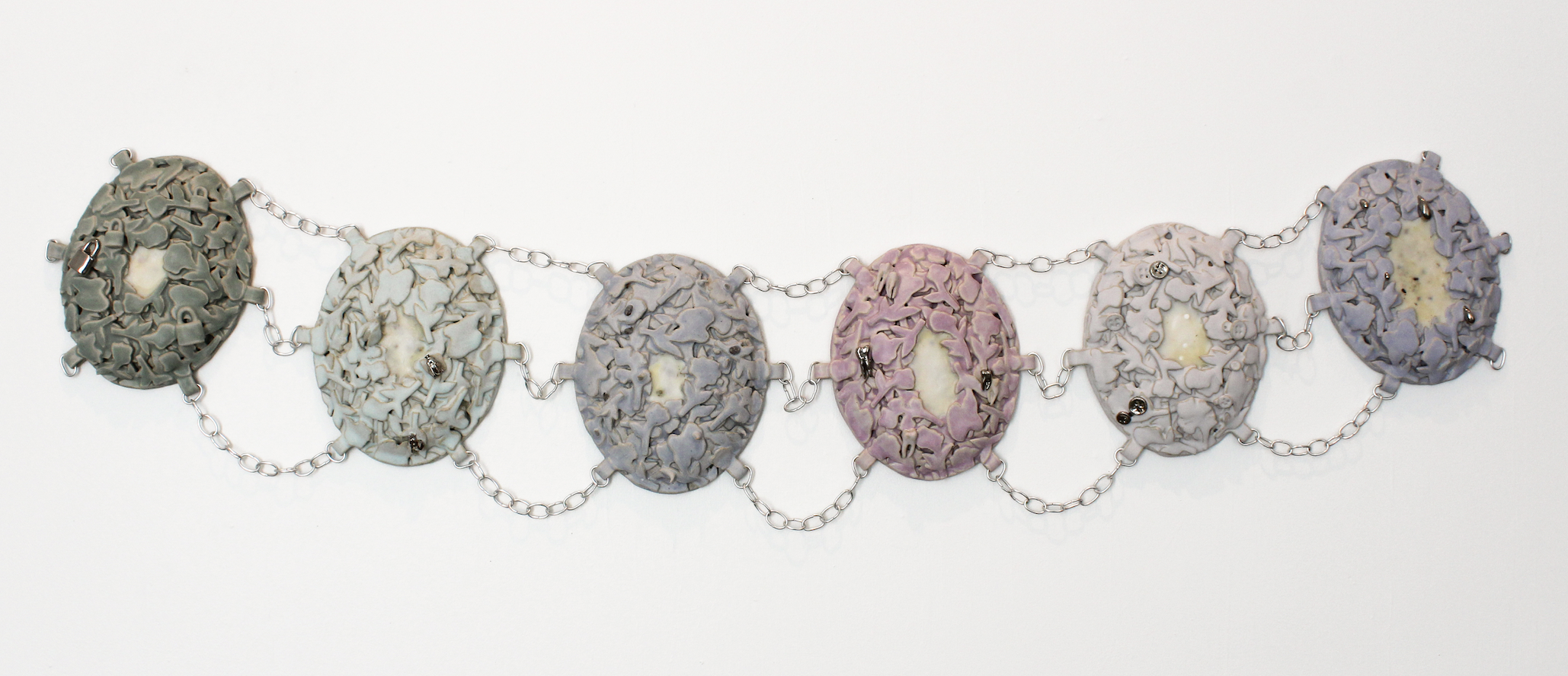 Abbey Peters, Heirloom: To Hide and To Hold, 2025, ceramic, glaze, luster, wire, beeswax, abortifacient herbs, birth control and morning-after pills, 3" x 16" x 72"