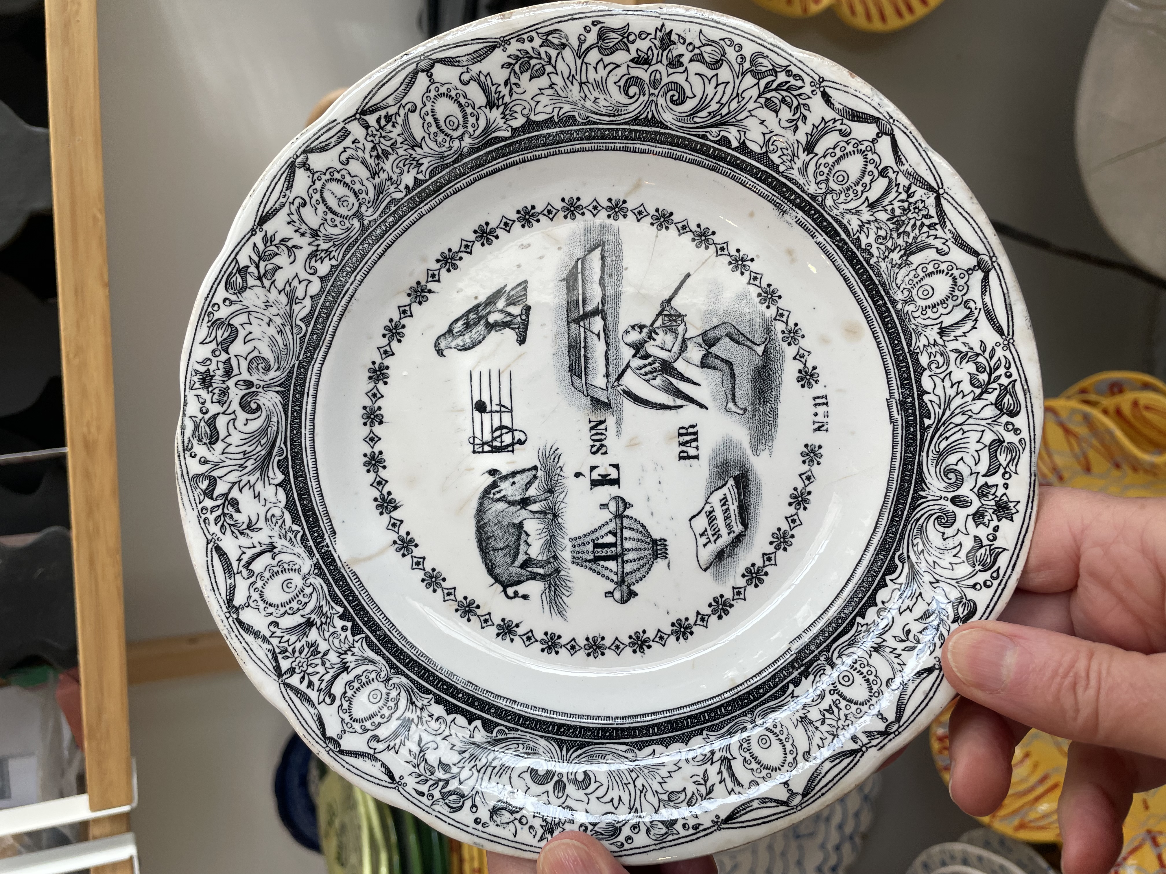 For the Curious – The Inspiration. Dessert Plate. transferware, “Porcelaine Opaque de Gien”, France, late 19th C 19.8 cn (7.8 in) diameter   Reverse: “Les Rebus illustres sont fort a la mode par le Temps qui court.” French rebuses are “sounds like” rather than “spelled like”- Portrayed is a female boar so not sanglier, but laie; the method of naming musical notes using syllables is called solfège – this is the musical note ré; in France a buzzard /hawk is buse; IL on the lustre (chandelier);  fort (like a fort itself) means strong; the letter A applies to the next image – the journal La Mode; finally, the figure of father time running (time is running out or how time flies).